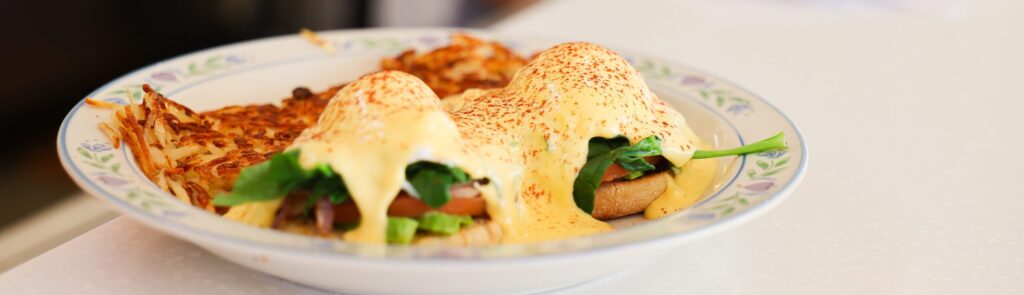 Garden Benedict at The Cup Café with poached eggs, spinach, avocado, and hollandaise.
