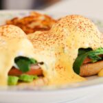 Garden Benedict at The Cup Café with poached eggs, spinach, avocado, and hollandaise.